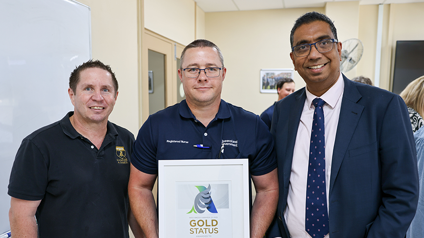 Three men standing with a gold award