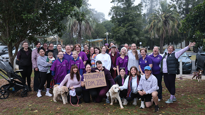 Large group of women stood together outside holding a sign for International Day of the Midwife