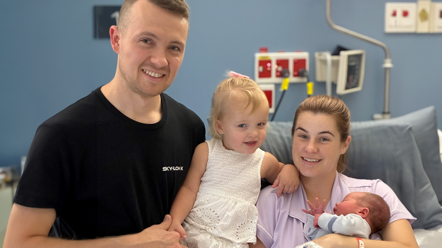 A man, a girl, a woman holding a baby