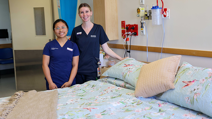 Two nurses standing beside a large double hospital bed