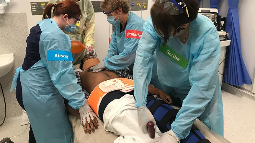 4 hospital staff performing a real-life clinical scenario on a patient in a hospital bed